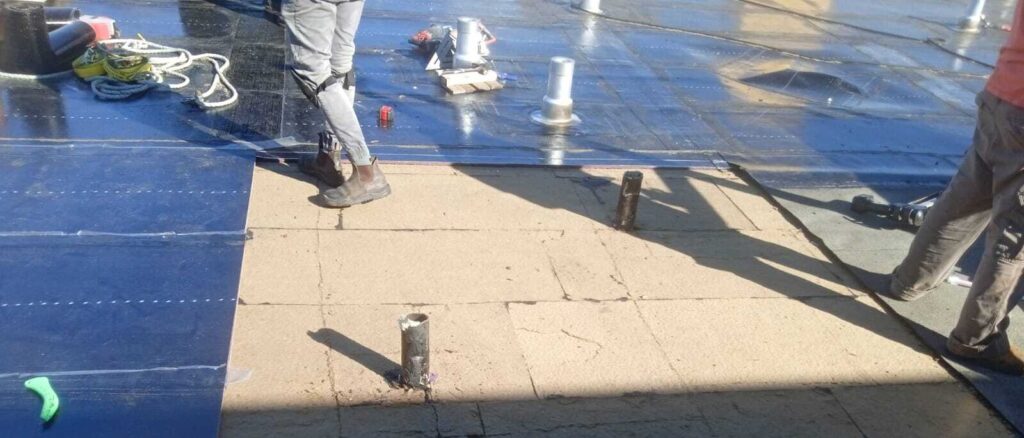 Roofing contractors performing roof repair on a flat building.